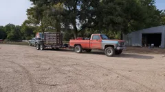 Squarebody Chevy and trailer hauling the panel set down a gravel farm road